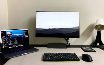 a desk with a laptop, keyboard, mouse and monitor